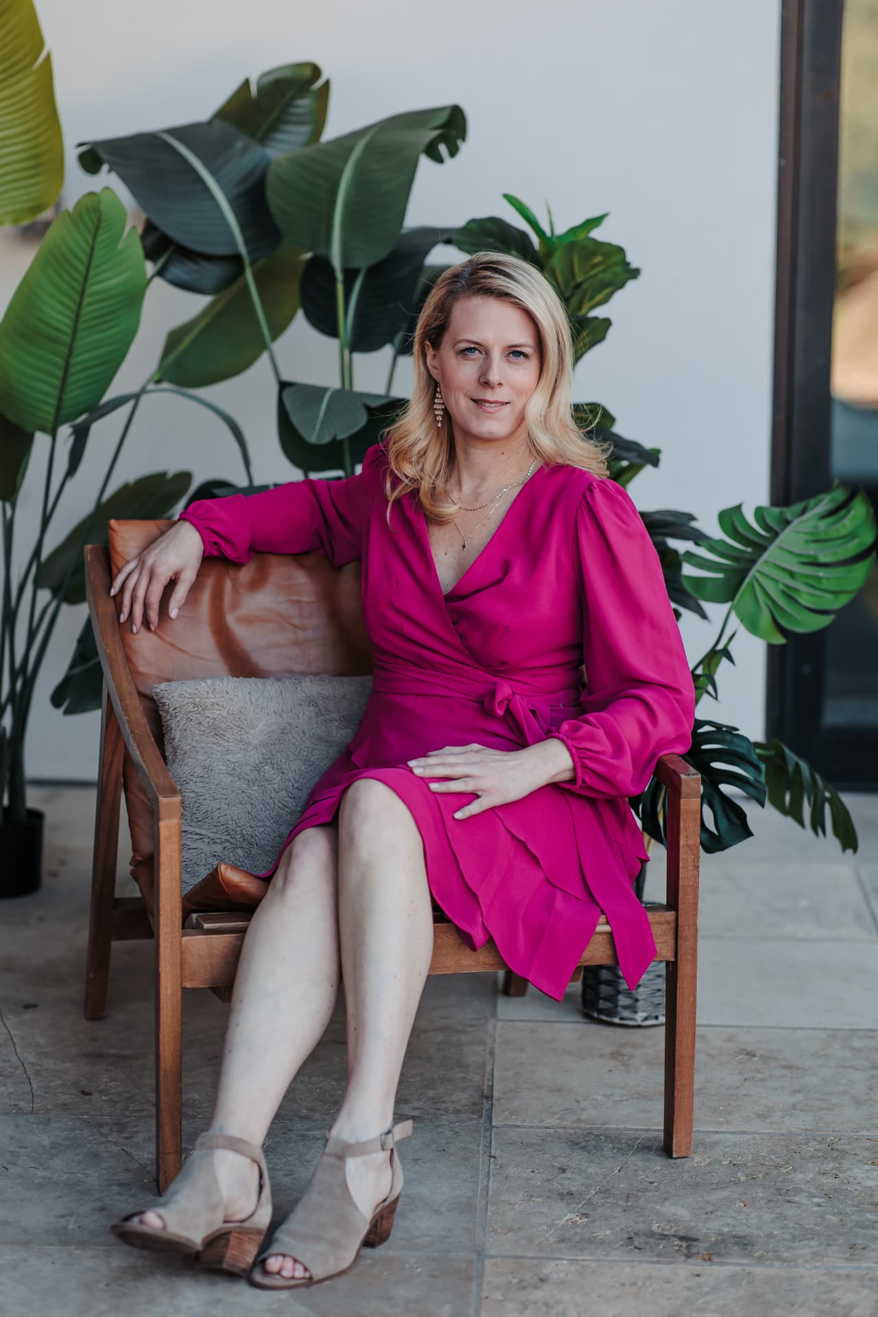 Allison Bridges, founder of Curl Evolution, seated in a magenta dress with tropical plants behind her